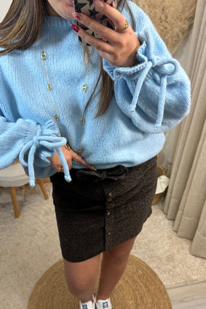 Detail de la jupe cleo en velours leopard chocolat avec des boutons sur le devant et pull léa bleu avec les noeuds et les froufrou au bout des manches 